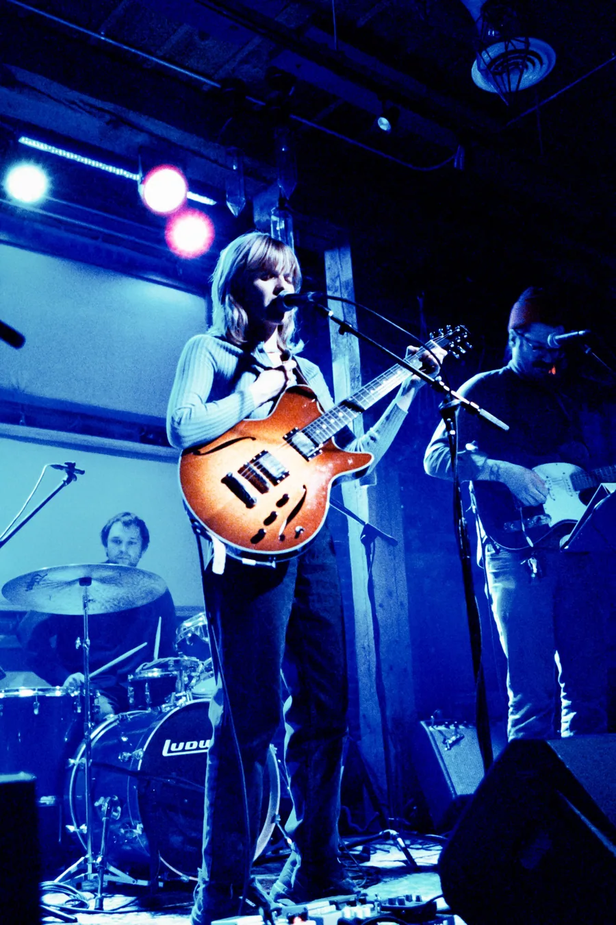 A musician playing guitar on stage under blue lights.