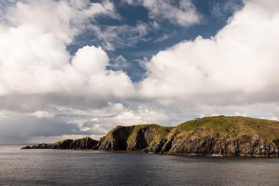 Clouds over a quiet coastal headland and open water.